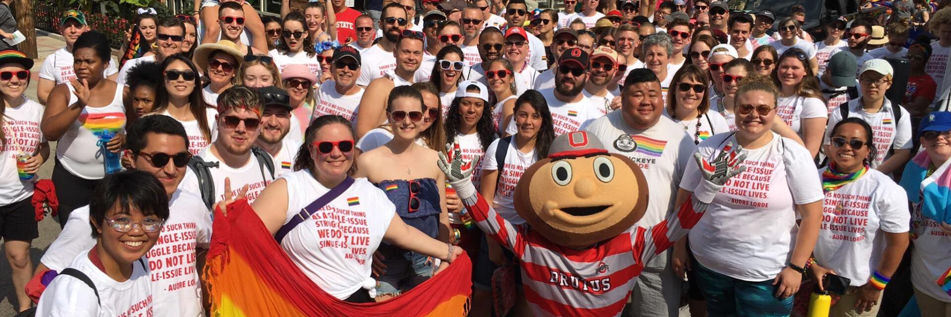 A large group of people and the mascot Brutus Buckeye posing for a photo at an LGBTQ Pride March